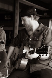two men playing acoustic guitars in a bar